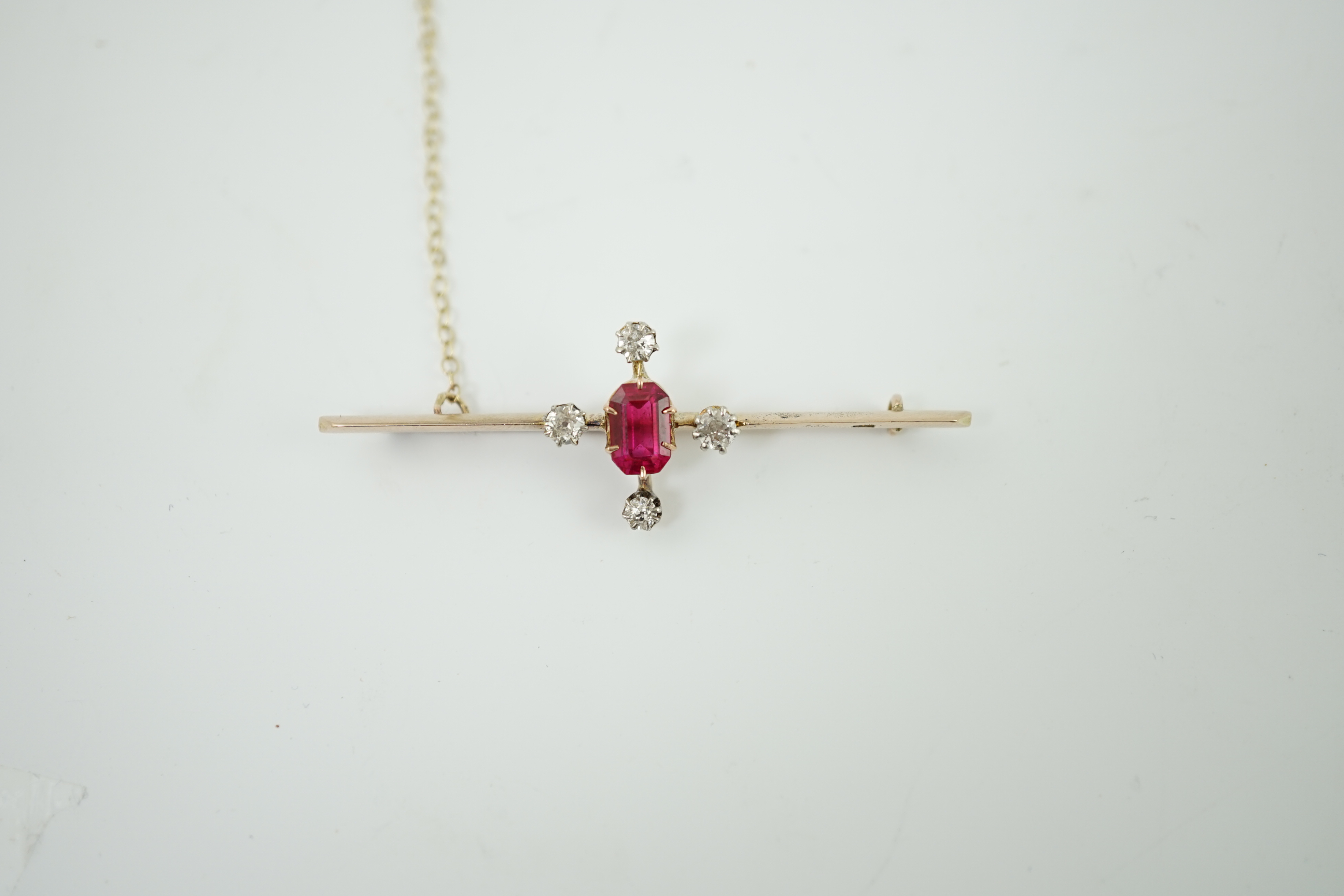 An early to mid 20th century gold, single stone oval cut synthetic ruby and four stone round cut diamond set bar brooch